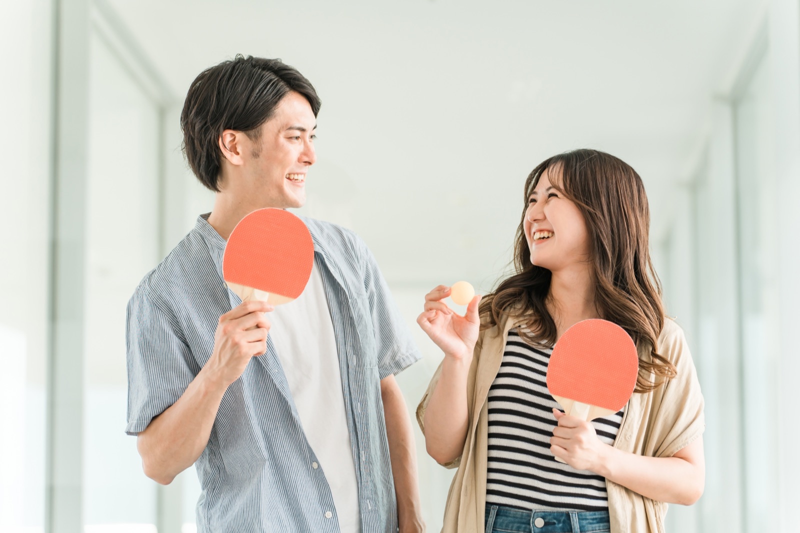 卓球ラケットとボールを手に笑顔で話す男女